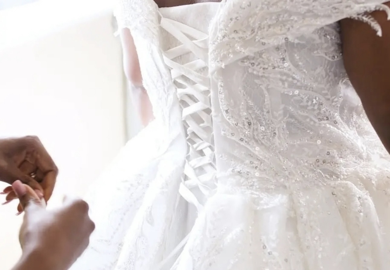 Lace-up back of a beaded lace wedding dress being fastened